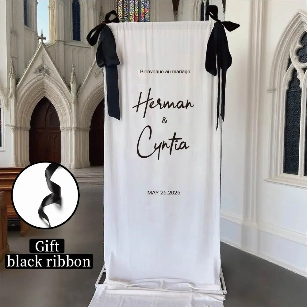 panneau de bienvenue de mariage personnalisé en tissu, avec une bannière en tissu blanc et une inscription en lettres cursives noires lisant « bienvenue au mariage herman and cyntia » (25 mai 2025), nouée en haut aux coins avec des rubans noirs, présentée dans un cadre d’église