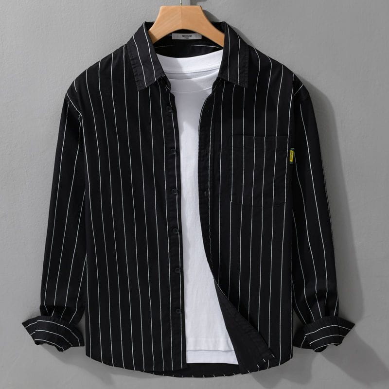Schwarz-weiß vertikal gestreiftes langärmliges Hemd im Casual-Stil mit Knopfleiste vorne und Kragen, auf einem Holzkleiderbügel präsentiert.