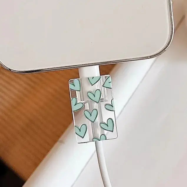 clear plastic tpu cable clip with mint green heart pattern holding a white charging cord for iphone charger protector 4 pack wrap.