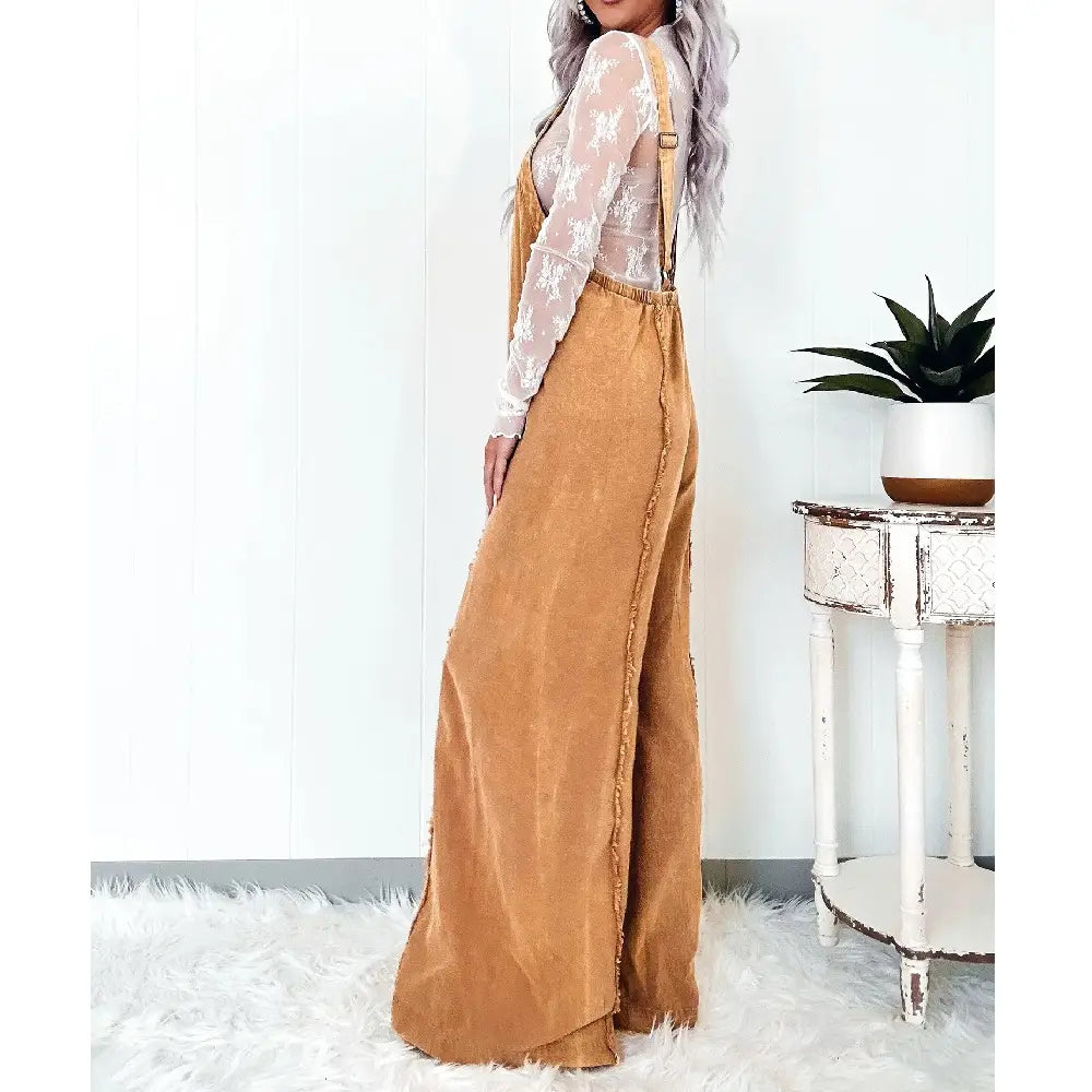 Women wide-leg denim jumpsuit featuring tan corduroy material with adjustable shoulder straps and a frayed hemline.
