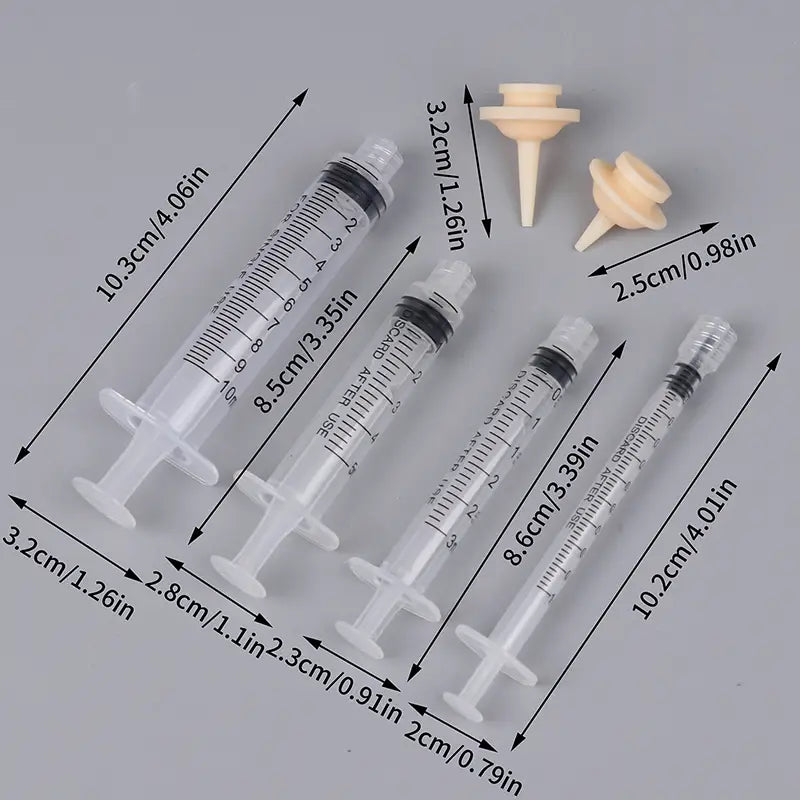 set of four clear plastic pet oral syringes with black rubber plungers and measurement markings accompanied by two beige silicone nipples for feeding.