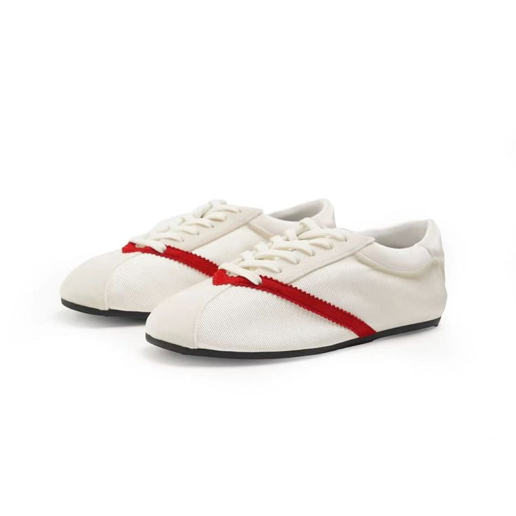 Baskets décontractées en cuir pour femmes en toile blanche, avec une bande rouge audacieuse sur le bout et le côté, dotées de semelles en caoutchouc noir.