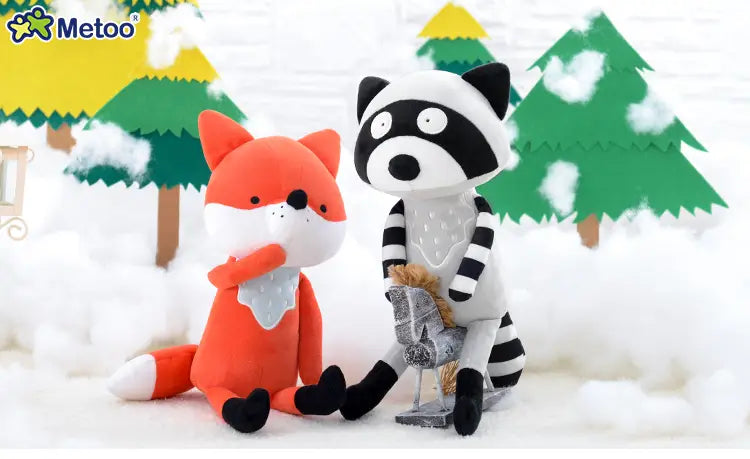 cute stuffed animal fox plush toy 33cm in orange with black accents and white muzzle sitting beside a raccoon plush toy in a snowy forest setting.