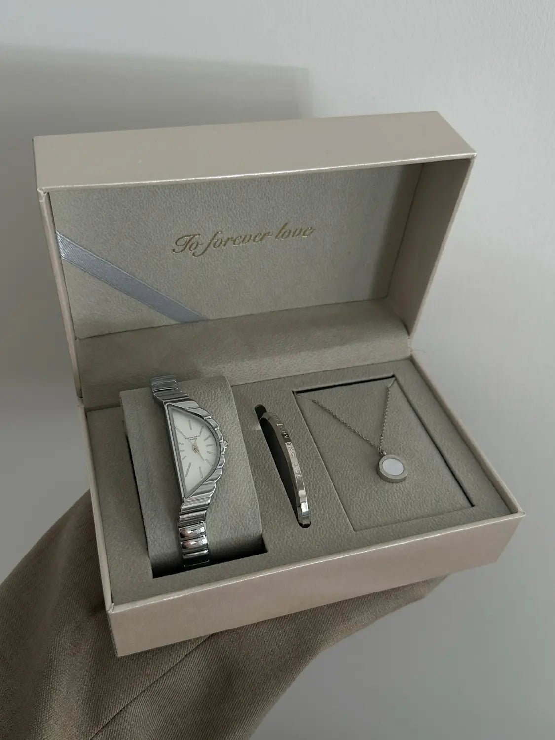 silver-toned geometric triangle quartz watch with a textured stainless steel band and minimalist dial displayed in an elegant gift box with matching jewelry