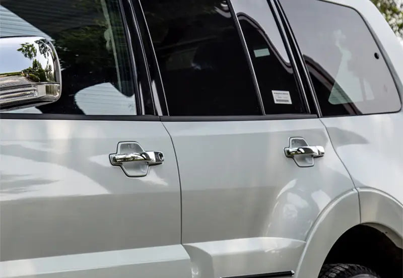 Poignées de porte finition chrome sur un SUV Mitsubishi Pajero argenté, comprenant une garniture de poignée de porte en chrome pour les années modèles 2007 à 2021.