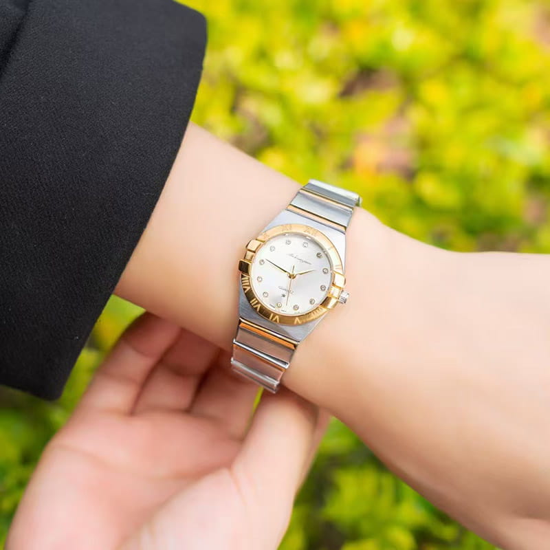 Un elegante reloj de cuarzo para mujer Omega bicolor de acero inoxidable con caja plateada y dorada, bisel engastado con diamantes y una esfera blanca con números romanos.