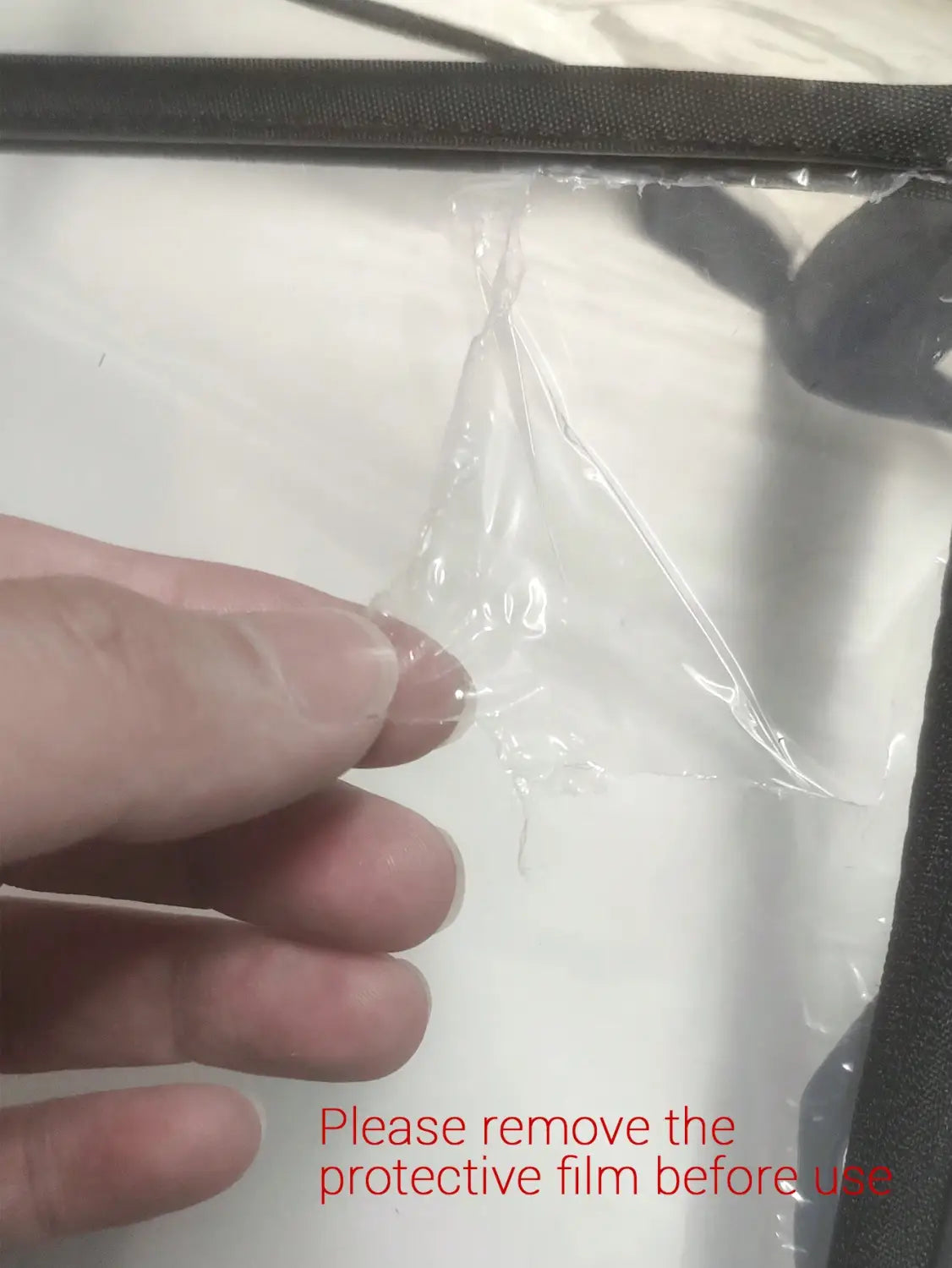 Klare, schützende Kunststofffolie, die von einer universellen transparenten Regenschutzabdeckung für Kinderwagen abgezogen wird, sodass ihr glattes transparentes Material und die schützende Eigenschaft sichtbar werden