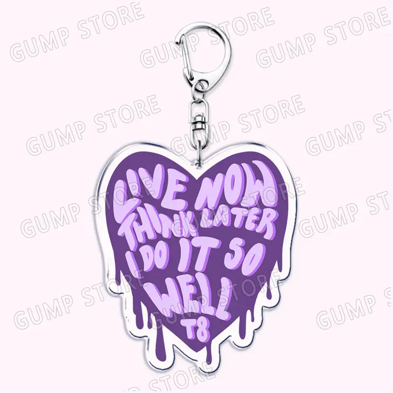 Purple heart-shaped acrylic Tate Mcrae keychain with silver metal clasp featuring a lighter purple dripping paint effect and the phrase live now think later do it so well t8, designed as a music fan gift.