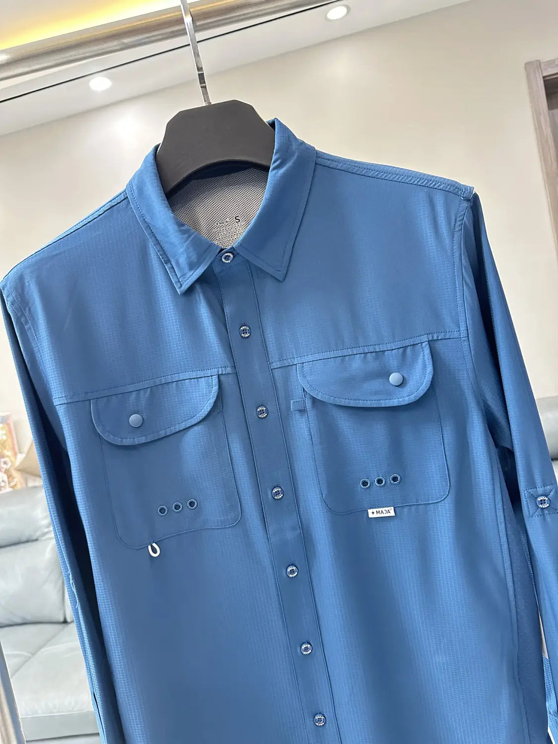 A light blue men’s tactical outdoor long sleeve shirt made of subtle textured fabric featuring two chest pockets and button-up front.