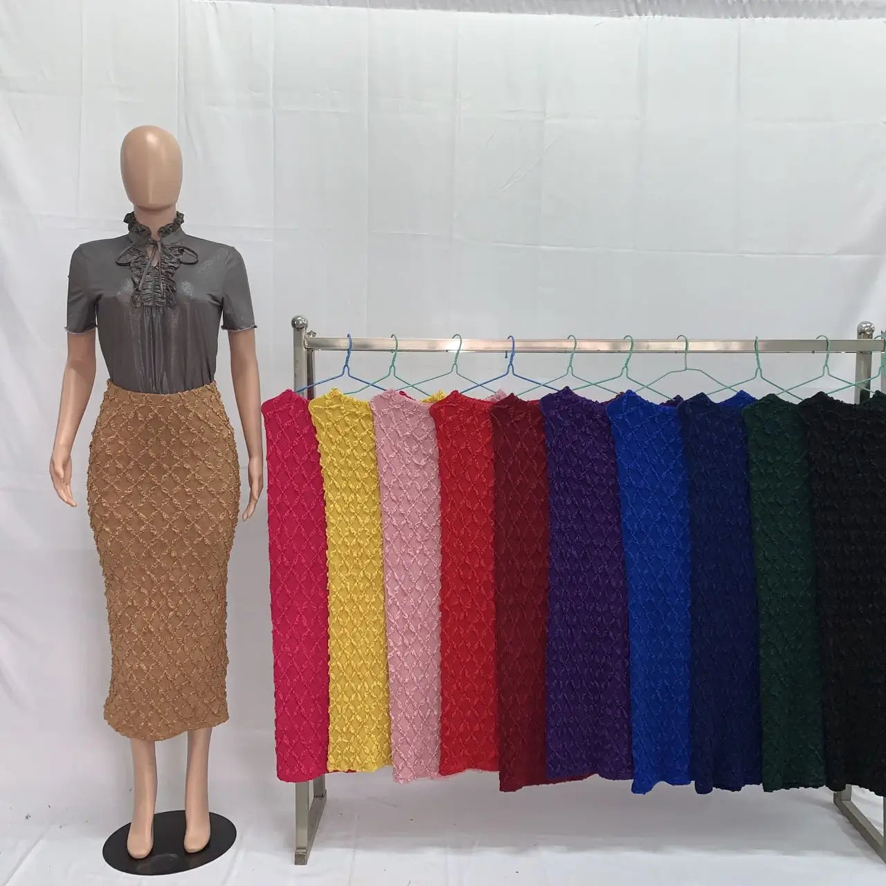 The mannequin wears a gray short-sleeved blouse paired with a brown high waist knit midi skirt featuring a slim fit and textured fabric.