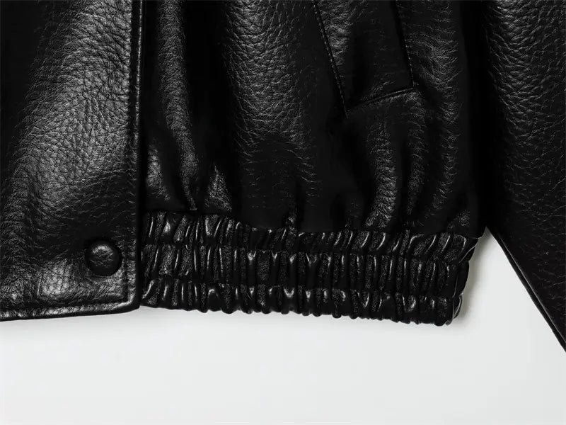 背面から見せた、凹凸のあるテクスチャーの表面と伸縮性のあるカフを備えた黒のフェイクレザーボンバージャケット。