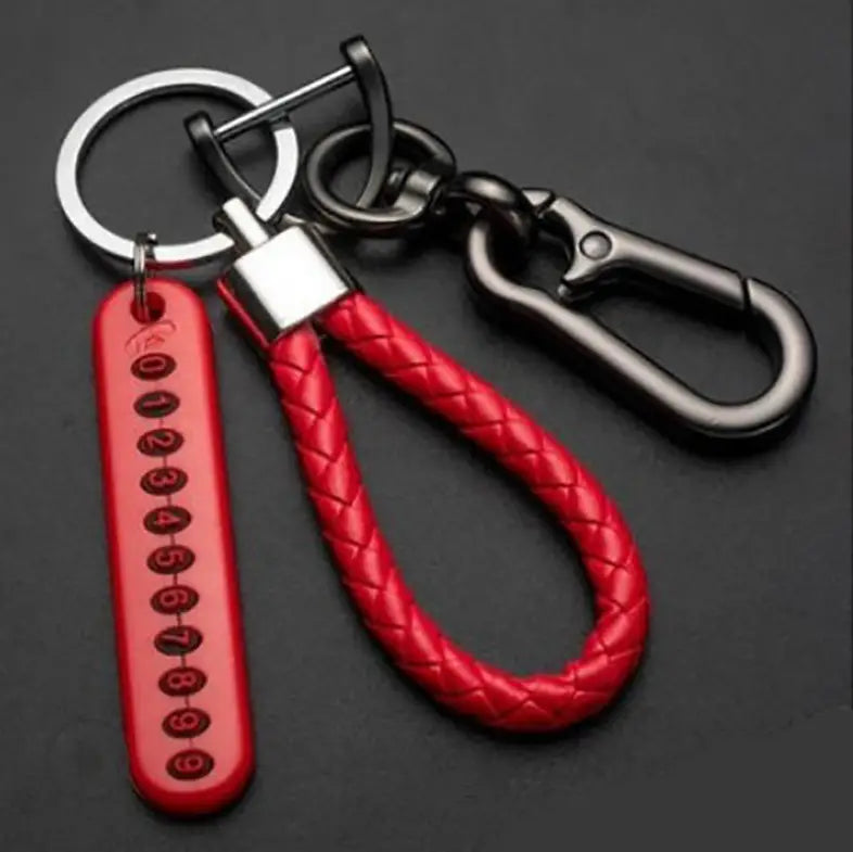 Red braided leather anti-lost stainless steel car key ring pendant with a silver-toned metal clasp and carabiner featuring an attached red plastic tag engraved with numbers 0 through 9.