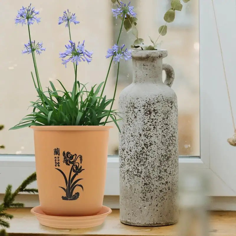 黒い花柄および中国文字のデザインが施された、桃色のプラスチック製ラン鉢に、マッチするトレーを組み合わせたもの。植物の育苗用鉢および苗用鉢として理想的です。