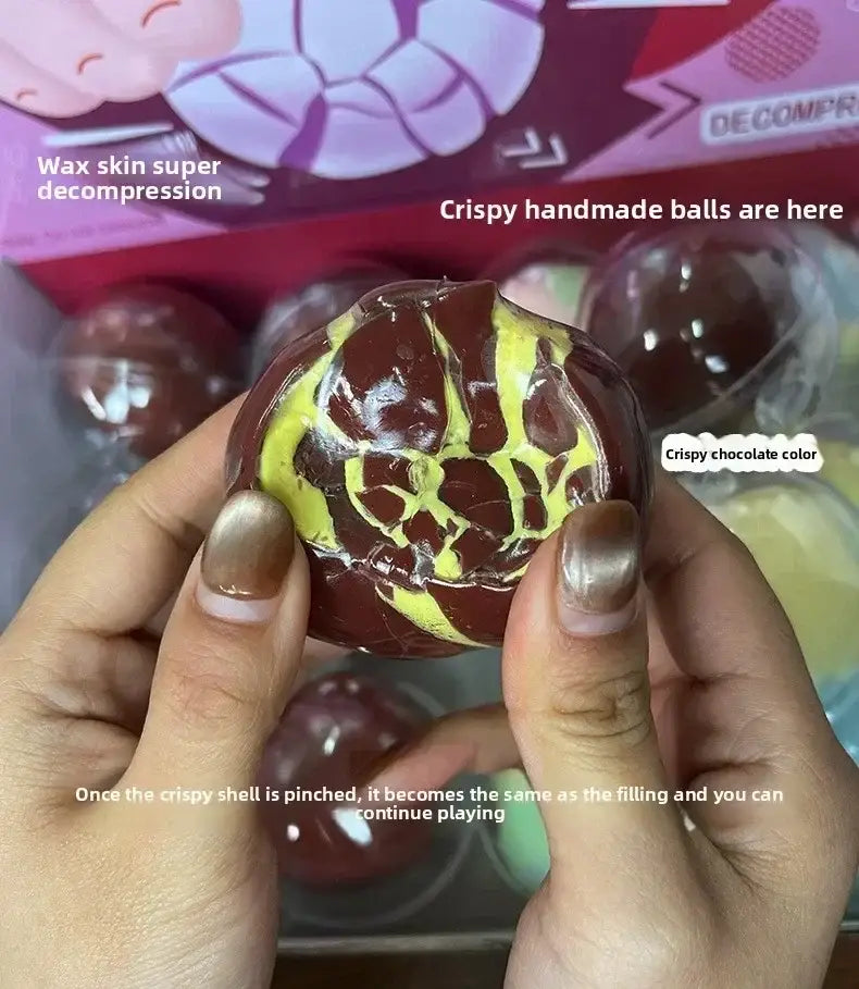 Un juguete sensorial antiestrés tipo pelota crujiente brillante, de color chocolate oscuro, con una cáscara amarilla marmoleada agrietada.