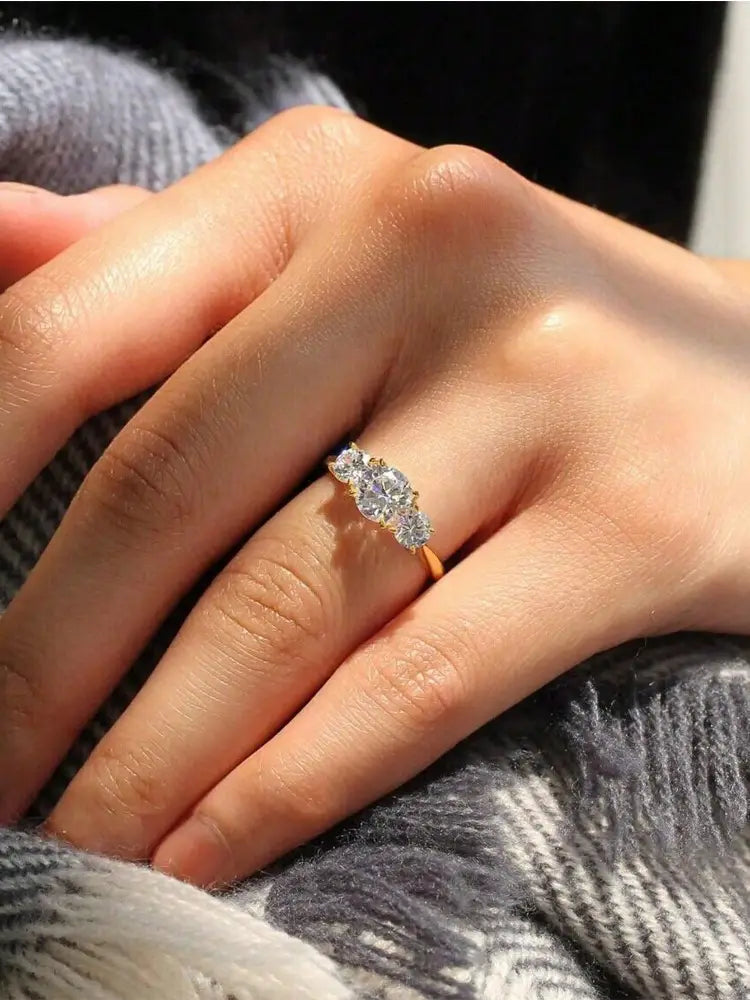 A sterling silver zircon ring for women featuring a delicate gold band with three sparkling round-cut diamonds in a classic trio design.