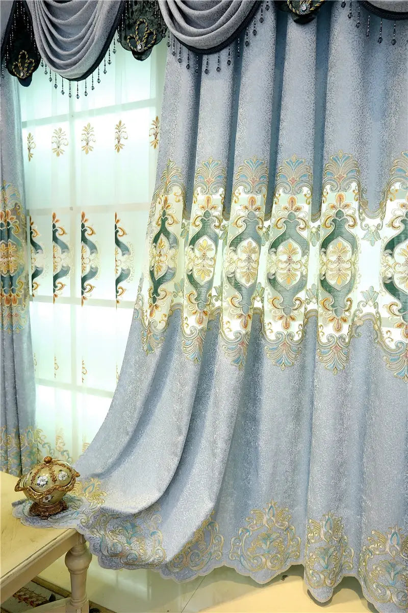 Light blue velvet embroidered living room curtains for french window with intricate gold and green patterns and a decorative valance featuring black trim.
