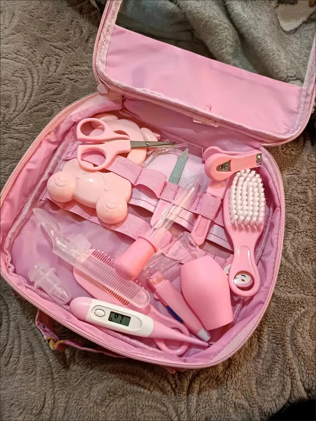 pink baby healthcare grooming kit 12 piece set featuring a cute bear-shaped nail clipper, scissors, brush, thermometer, and other essentials organized in a matching pink organizer.