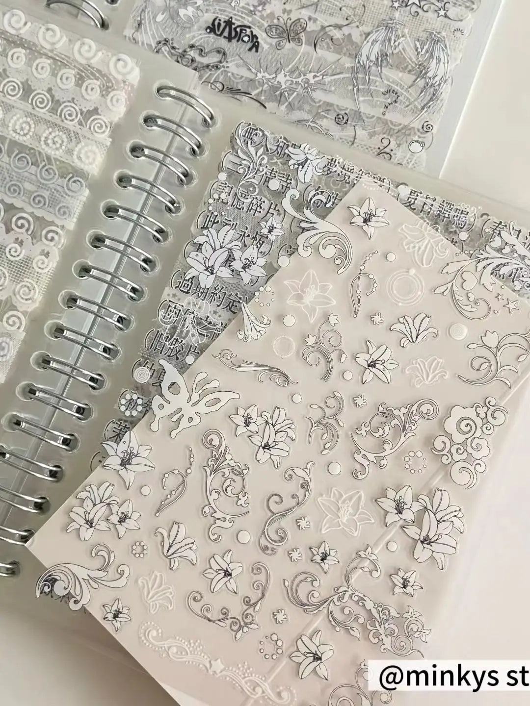 Klarer Planer mit silberner Spiralbindung und schwarzen, weißen und grauen floralen Stickern aus der Kollektion „Kawaii Kpop Sticker Book Spiral Journal Stationery“.