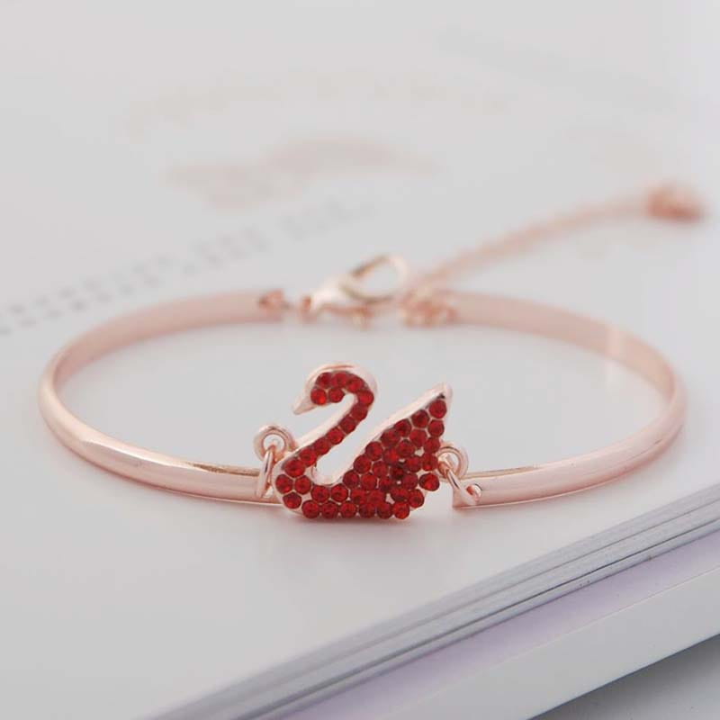 Bracelet jonc avec breloque de cygne en cristal en or rose, orné de strass rouges.