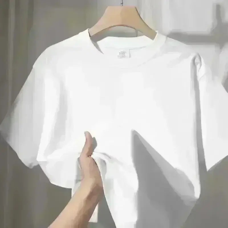 Camiseta de algodón oversize blanca y de corte pulcro con detalle de pájaro bordado colgado en una percha de madera.