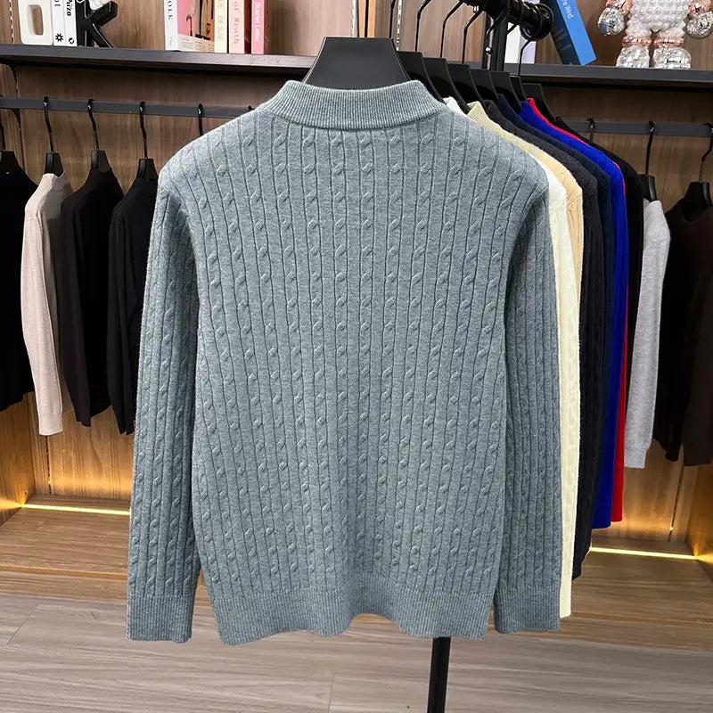 Ein hellgrauer Herren-Zopfstrick-Pullover mit Rundhalsausschnitt und geripptem Rundhalsausschnitt sowie Bündchen, an einem Schaufensterpuppen-Exemplar dargestellt.