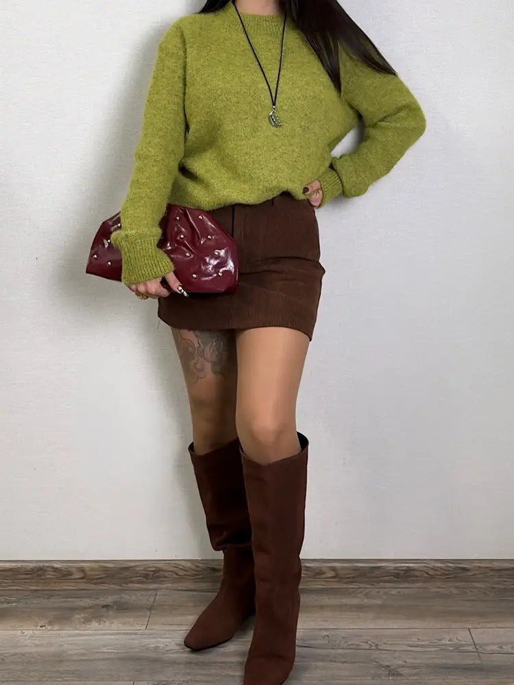 Eine glänzende Burgunderfarbene Clutch mit strukturierter, glänzender Oberfläche und dezenten Verzierungen, passend zu einem Damen-Winter-Strickpullover.