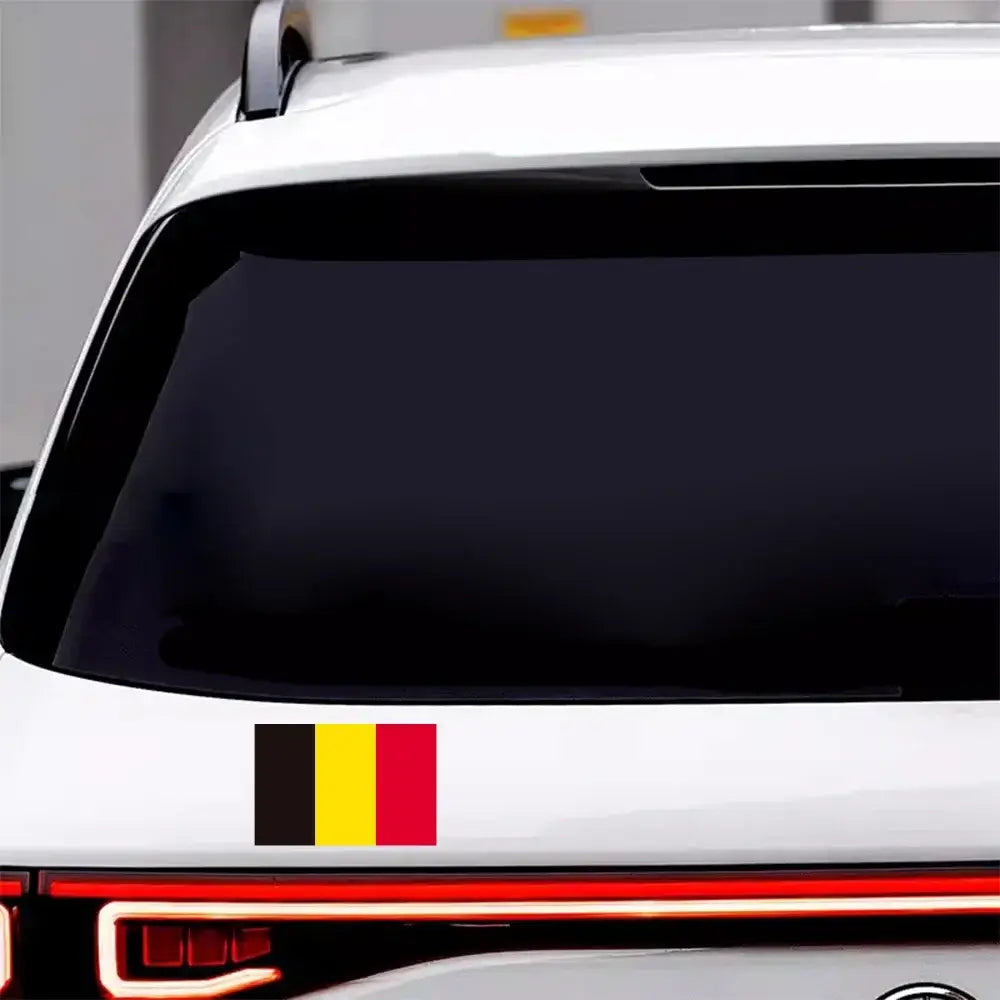 A rectangular Belgian flag car sticker with vertical black yellow and red PVC waterproof stripes adhered to the lower rear bumper of a white vehicle.