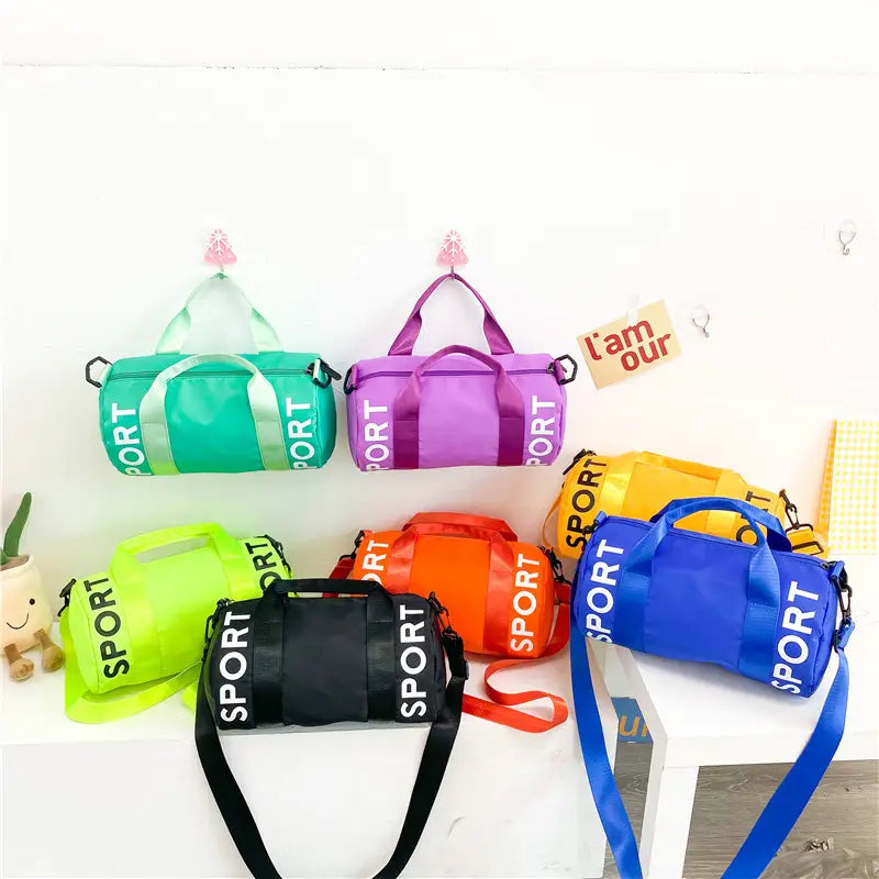 Eine Kollektion leuchtend farbiger zylindrischer Kinder-Sport-Reise-Sporttaschen in Grün, Lila, Gelb, Orange, Schwarz und Blau mit kräftiger Sportbeschriftung, entworfen für die Nutzung auf Reisen sowie als Crossbody für das Gym.