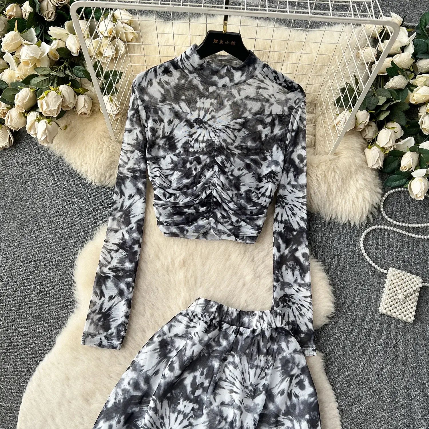 black and white tie-dye long-sleeved crop top with high neck and ruched front paired with a marble print two piece mesh skirt set featuring elastic closure type