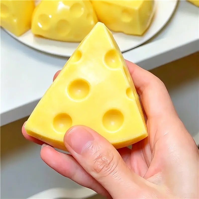 Un jouet sensoriel de type balle anti-stress en forme d’arachide jaune en forme triangulaire, avec des perforations caractéristiques rappelant le fromage suisse.
