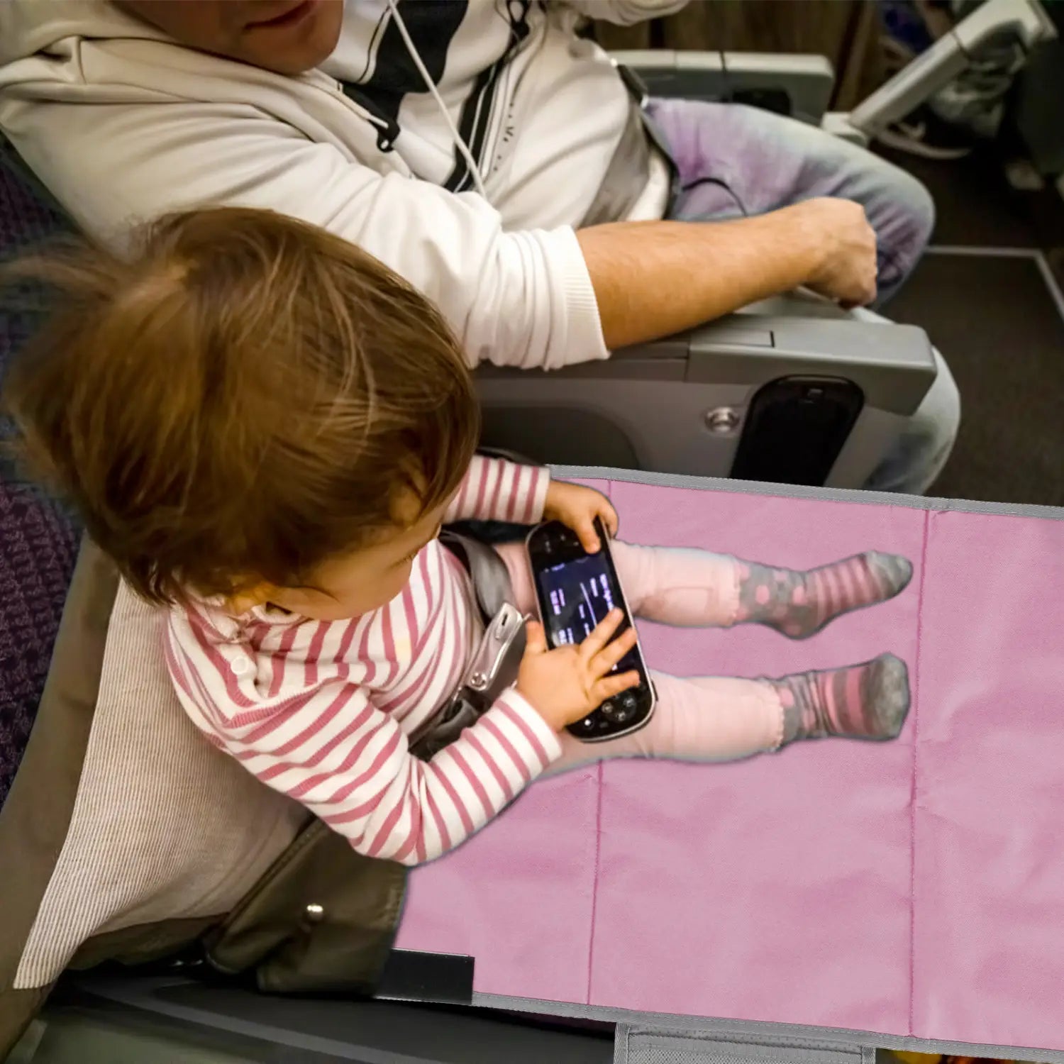 Rosa Fußstütze-Erweiterung für den Flugzeugsitz für Kleinkinder aus weichem Material mit einem gedruckten Motiv eines Kindes, das mit einem tragbaren Spielgerät spielt