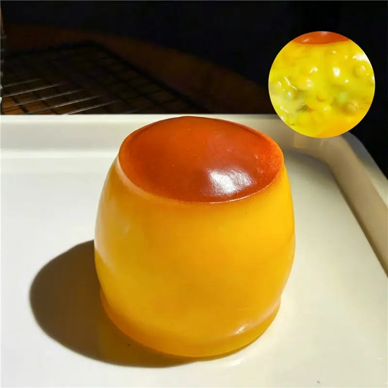 Un dessert en gélatine translucide orange et jaune en couches, évoquant une jouet sensoriel de type balle anti-stress en forme d’arachide, avec une surface lisse et brillante