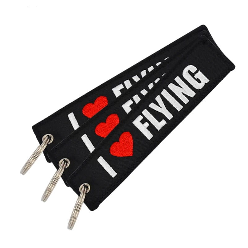 「i heart flying」の白い表記、赤いハート、銀色の金属リングを備えたフライト前に取り外してください。黒の刺繍キーチェーン。
