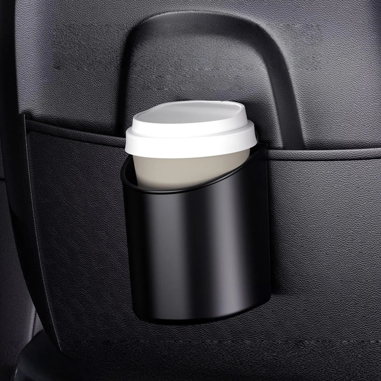 Black matte-finish car door cup holder securely grips a white-lidded coffee cup inside a vehicle.