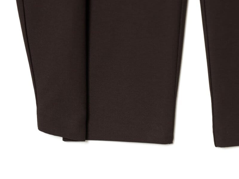 Pantalons taille haute plissés à jambes évasées marron foncé, avec une coupe droite sur mesure et un léger marquage le long de la couture latérale.