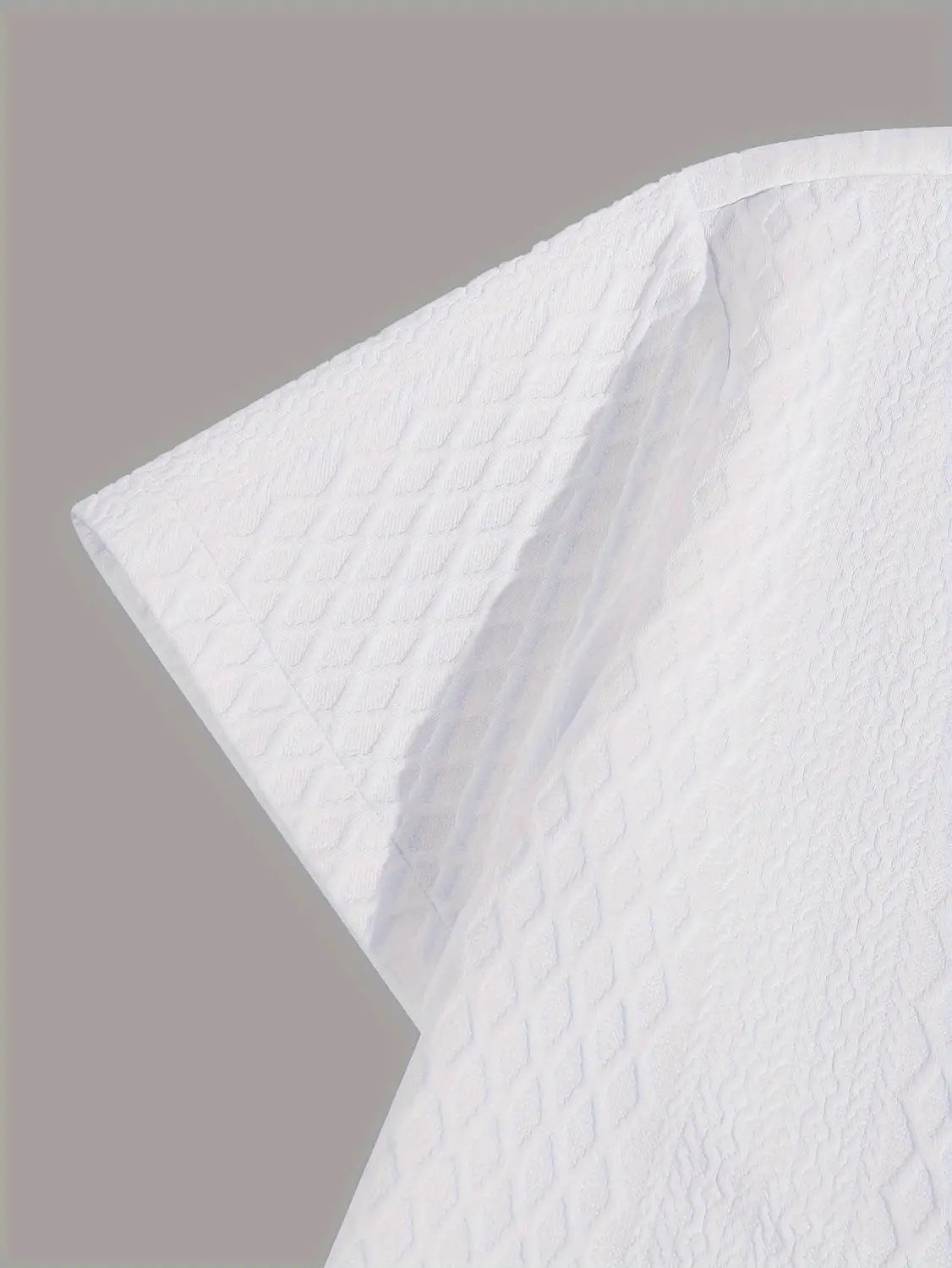 haut gris en maille diamant à manches courtes avec un essuie-tout blanc présentant une texture subtile à motif losange.