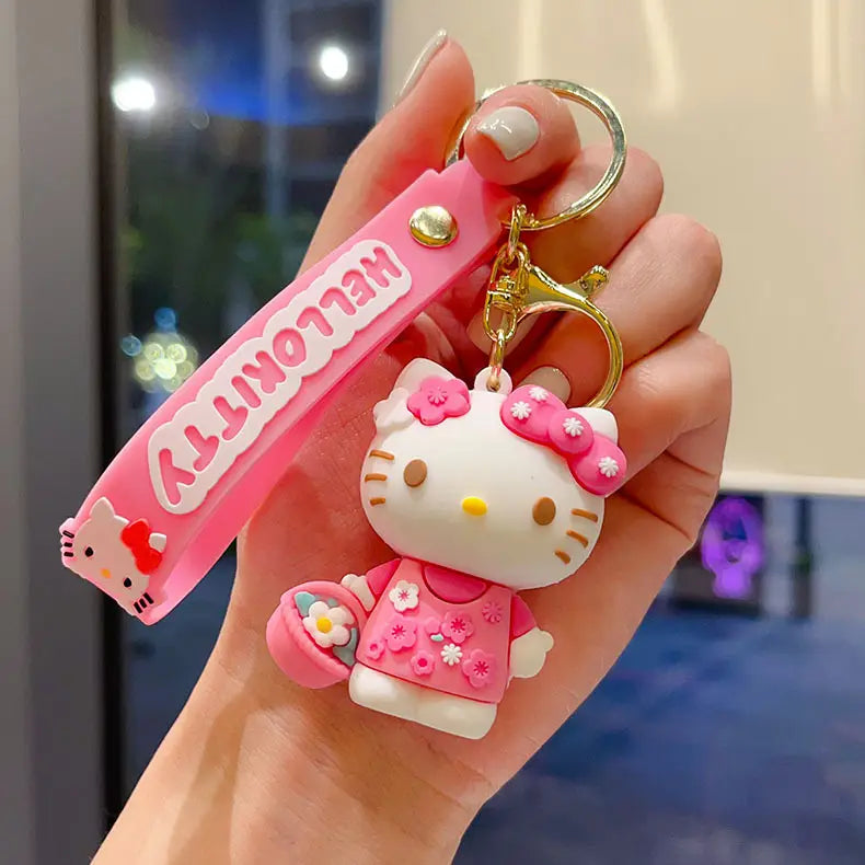 Pink silicone hello kitty cartoon keychain with gold-tone metal ring and clasp featuring hello kitty in a pink floral dress with small flower details for use as an anime bag charm.