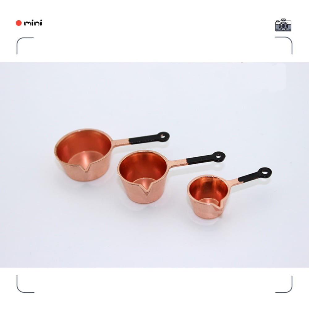 Ensemble de trois petites tasses à mesurer de cuisine miniature en cuivre pour maison de poupée, avec des poignées noires.