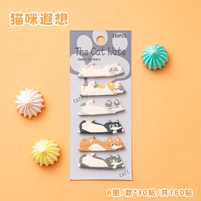 キャットメモパッド＆付箋セットの一部として、肉球プリントのアクセントが付いたグレーのカードに梱包された、さまざまなデザインの色鮮やかな猫をテーマにしたインデックスシール180枚セット。