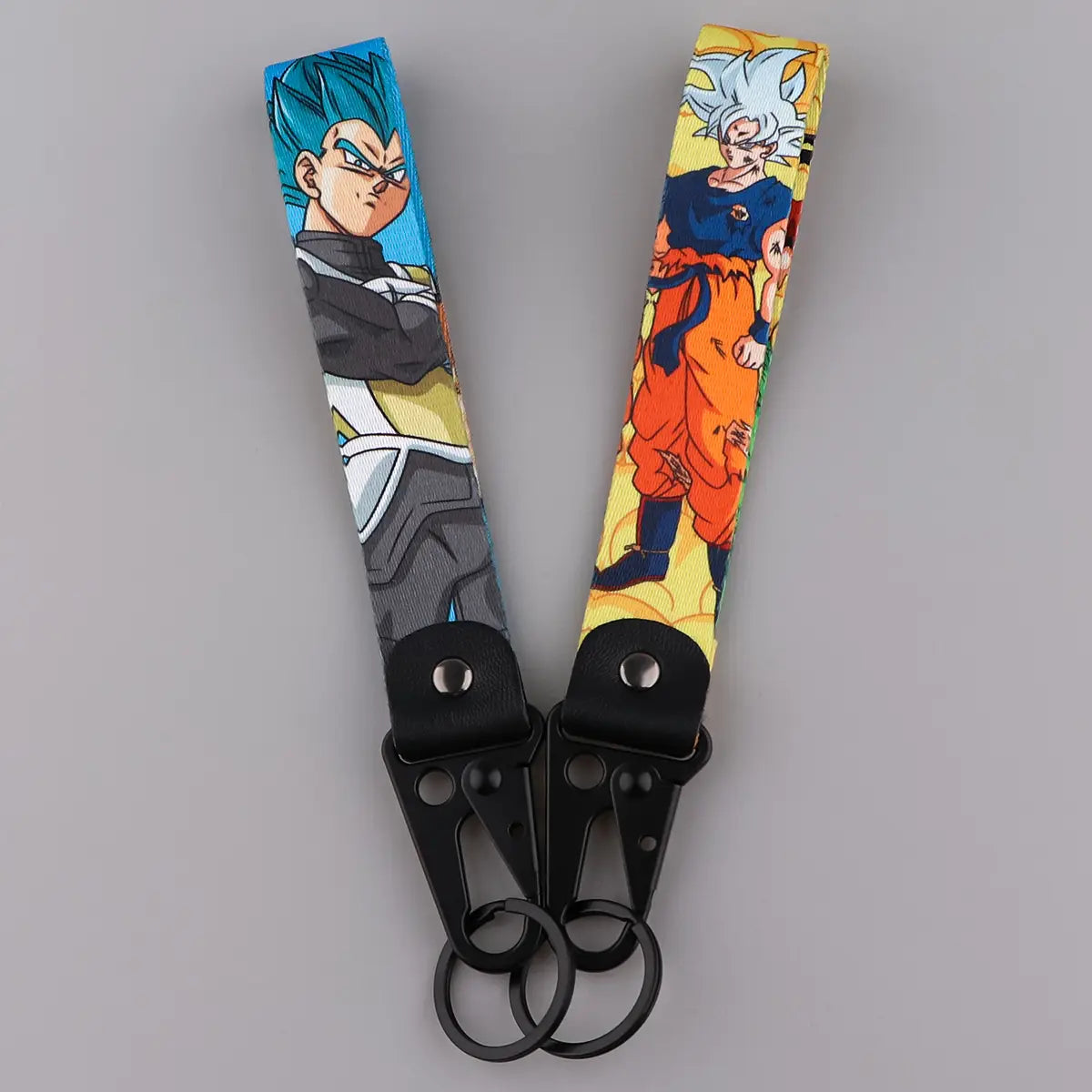 two colorful dragon ball z goku and vegeta fabric lanyard keychains featuring vegeta with blue hair and goku in super saiyan form printed on fabric straps with black metal clasps