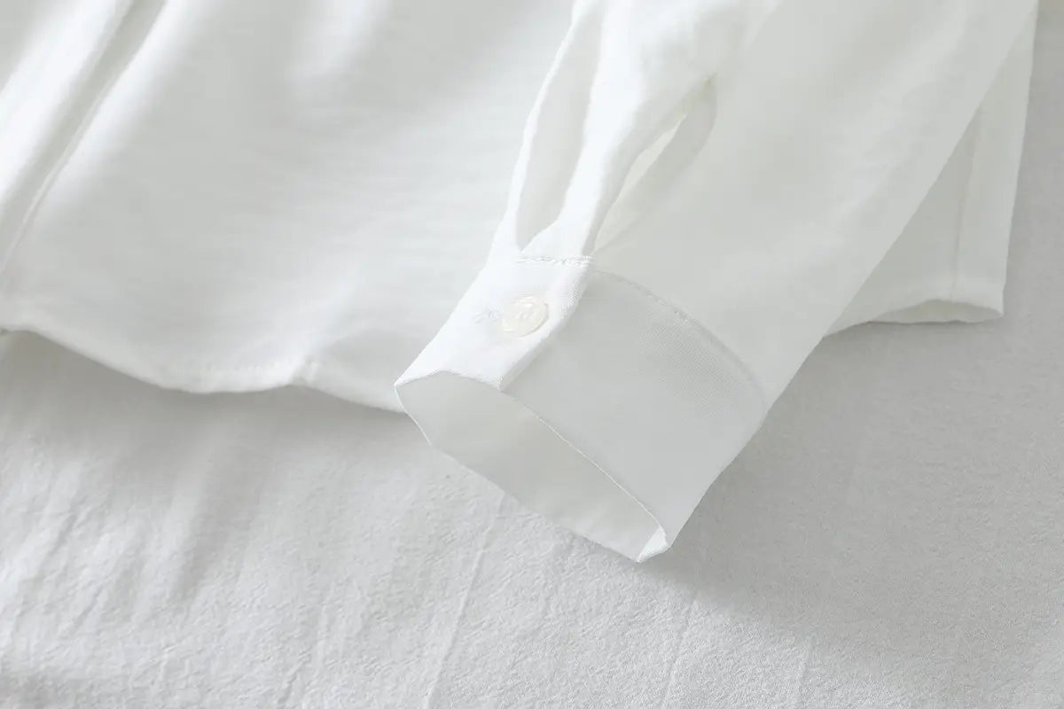 Weißer Leinenhemd-Ärmelabschluss mit einem einzelnen Knopf an einer Damen-Casualbluse aus Baumwollmischgewebe mit langen Ärmeln.