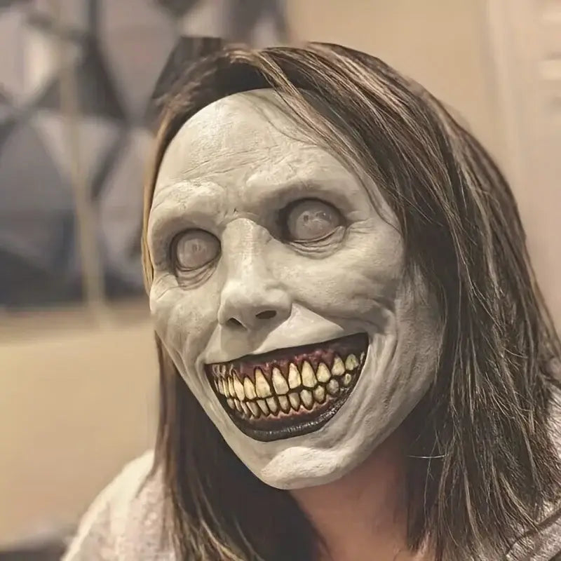 A detailed pale latex creepy Halloween resin horror mask with long dark hair and a wide unsettling grin featuring sharp teeth for full face costume accessory.