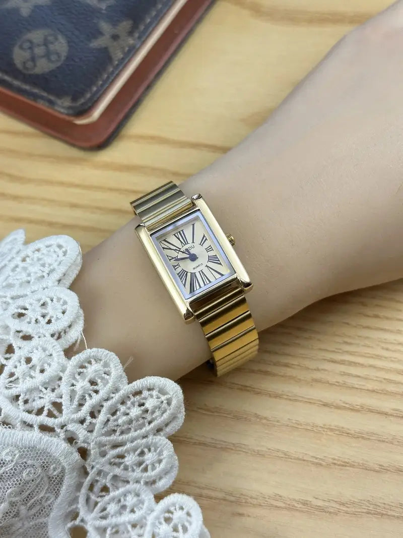 Vintage gold rectangular quartz watch for women with a gold-toned metal bracelet and a white dial featuring roman numerals.