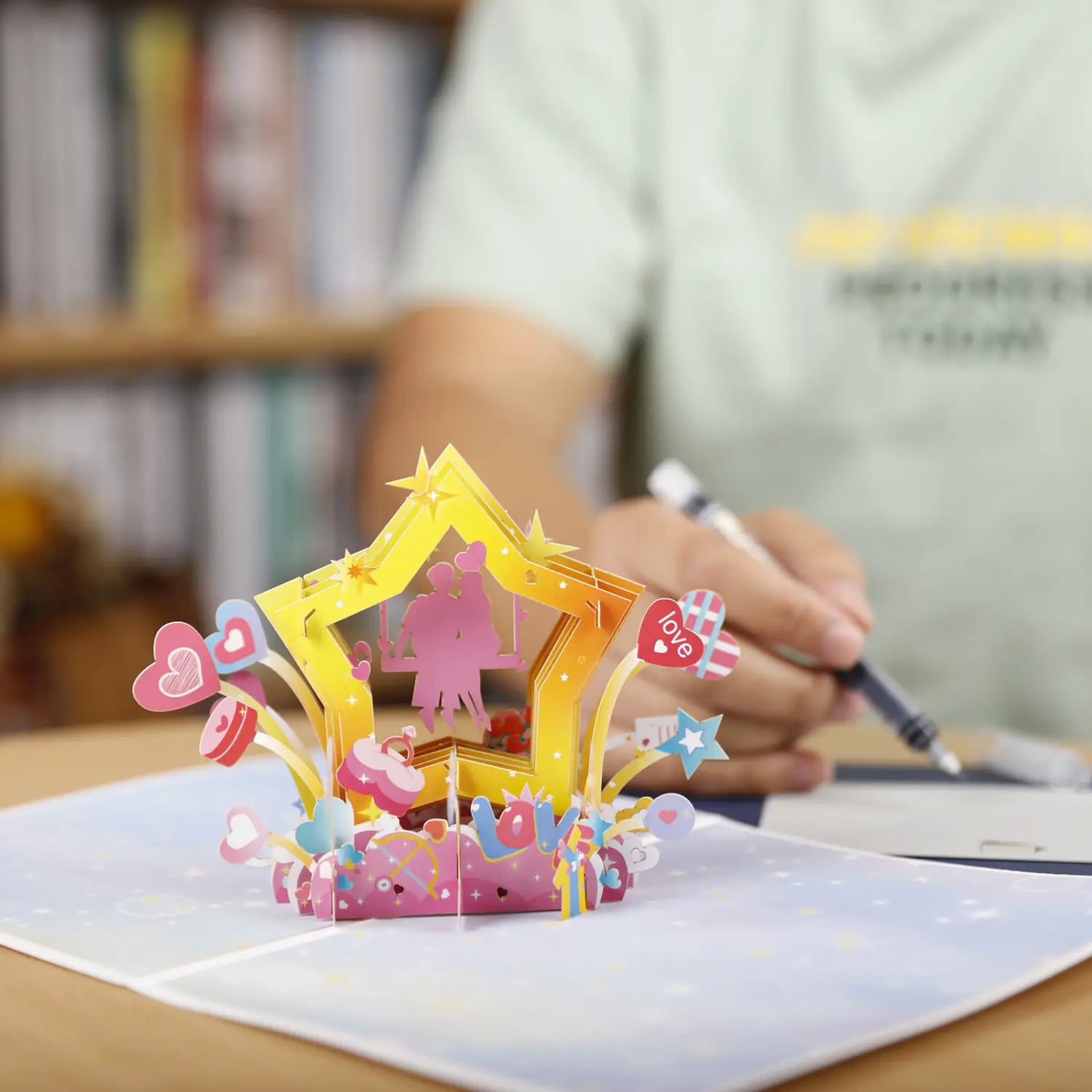 Carte de la Saint-Valentin 3D à effet pop-up vibrante jaune et rose, présentant la silhouette d’un couple romantique, des cœurs, des étoiles et le mot « love » dans un design ludique, pour une salutation et une célébration.