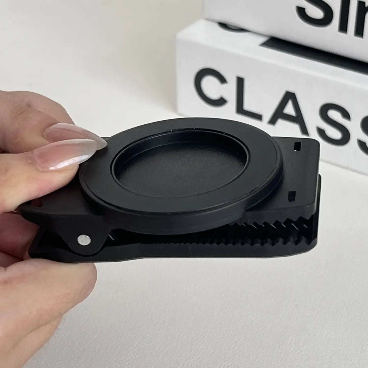Schwarzer Kunststoff-Magnet-Telefon-Rucksackclip mit kreisförmiger Klemme und strukturierter Griffigkeit zur Verwendung als Universalhalterung.
