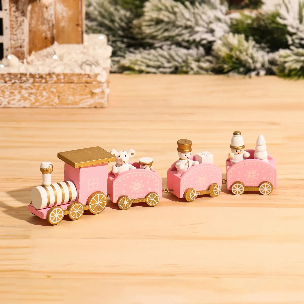 Pink wooden Christmas train toy with gold accents and miniature snowman passengers for holiday home decoration.