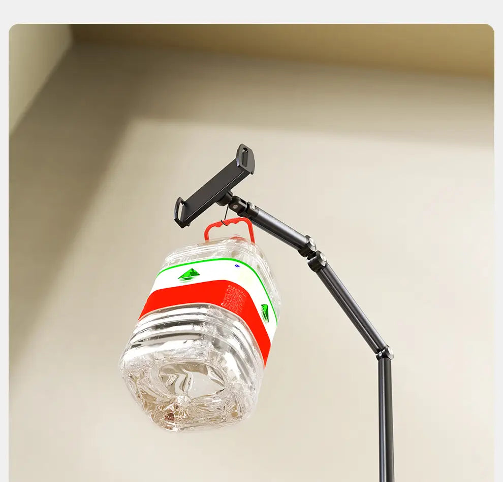 Clear plastic water bottle with red and white label hanging from black adjustable aluminum alloy tablet and phone floor stand.