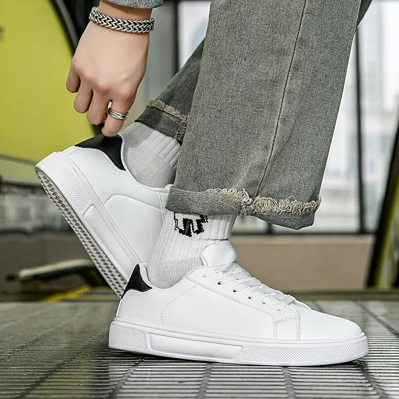 Weiße Ledersneaker im Freizeitstil, leichte Sportschuhe, mit einer klaren lederähnlichen Oberseite, weißem Low-Top-Design, schwarzen Akzenten an Ferse und Zunge sowie einer strukturierten Gummisohle.