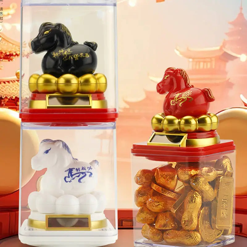 Schwarze, rote und weiße Keramik-Figurinenpferde mit goldenen Akzenten sitzen auf transparenten Behältern, gefüllt mit goldenen Erdnüssen, in einer Ausstellung mit chinesischer Tierkreis-Figurinenpferd-Sonnenglücksbringer-Zierpony.