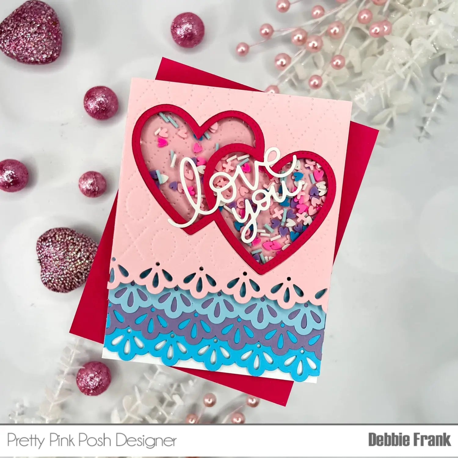 valentine metal cutting dies and clear stamps set featuring a pink and blue layered paper card with a red heart cutout revealing colorful confetti inside and love you in white cursive script.